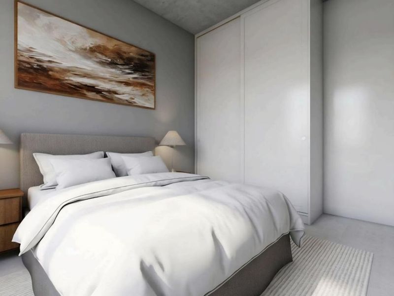 A modern, well-lit bedroom featuring a large built-in wardrobe with clean lines and a neutral color palette.