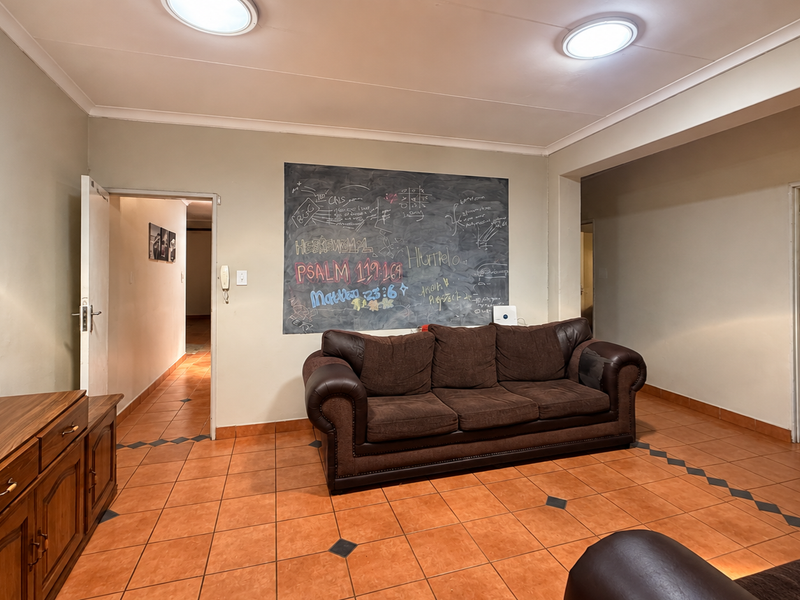 A living room featuring tiled flooring and recessed ceiling lighting, providing a functional space with neutral wall finishes.