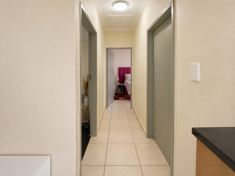 A clean, well-lit hallway featuring neutral tiled flooring and access to multiple rooms, providing a functional transition space within the townhouse.