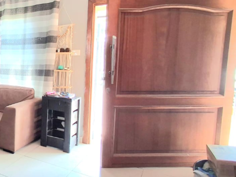 An interior view of the home entrance featuring a solid timber front door and tiled flooring.