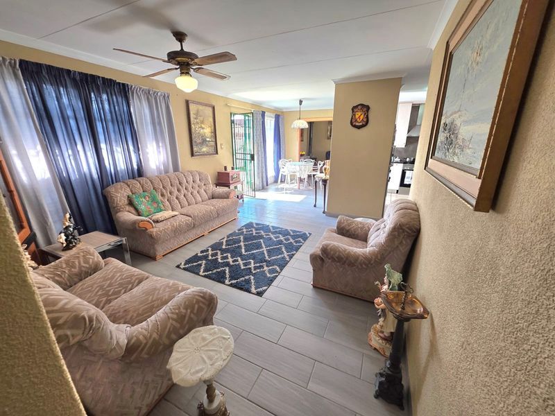 Open plan living area featuring tiled flooring, a ceiling fan, and direct access to the outdoor space through a security gate.
