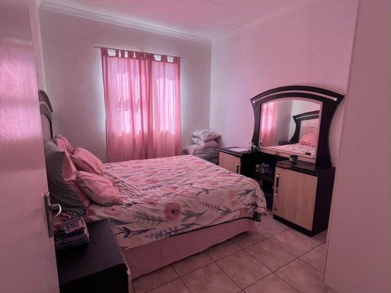 A bedroom featuring tiled flooring and a built-in wardrobe, offering a functional space with neutral wall finishes.