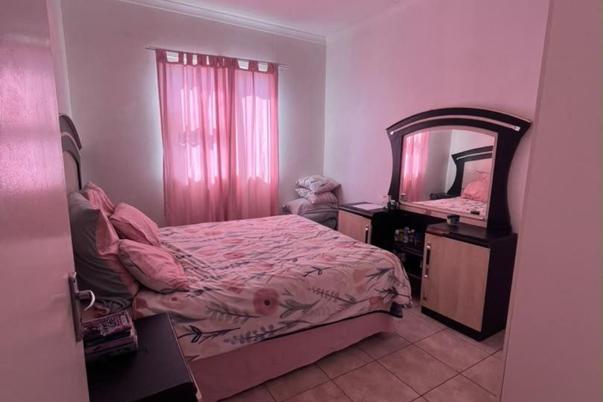 A bedroom featuring tiled flooring and a built-in wardrobe, offering a functional space with neutral wall finishes.