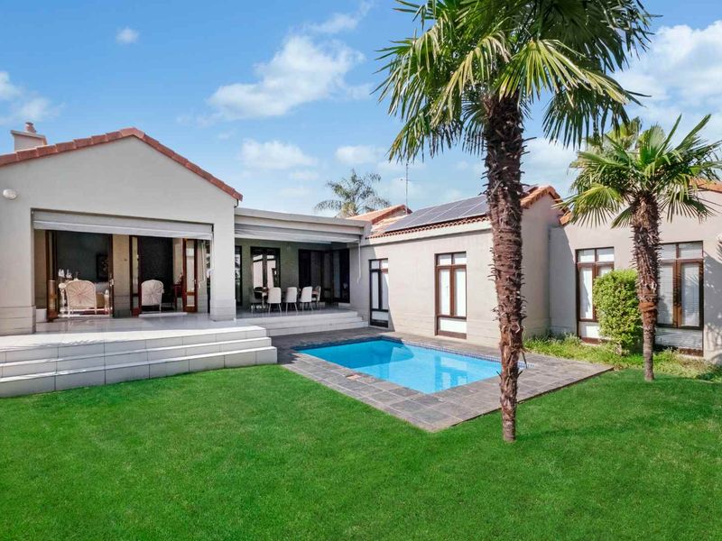 Rear view of the property featuring a swimming pool, tiled patio area, and well-maintained garden with solar panels installed on the roof.
