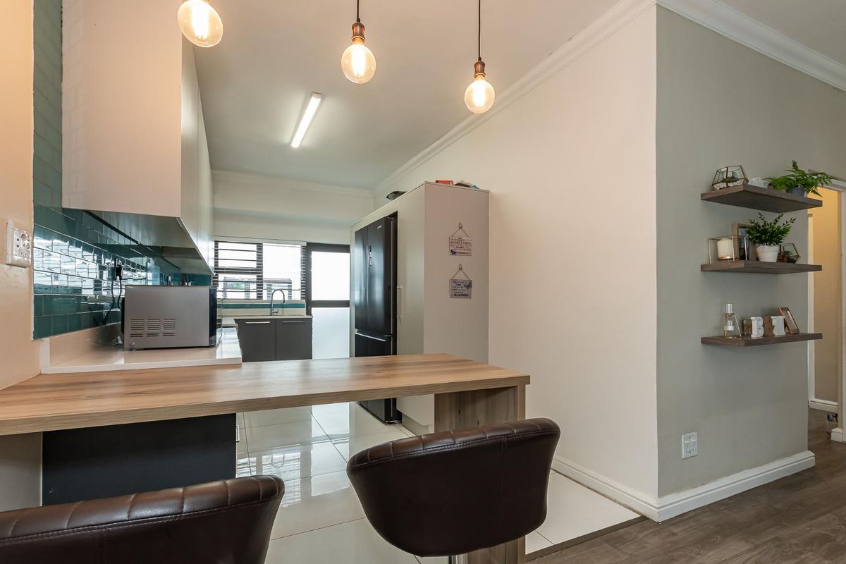 Modern kitchen featuring sleek cabinetry, tiled backsplash, integrated breakfast bar, and contemporary pendant lighting, creating a functional and stylish culinary space.