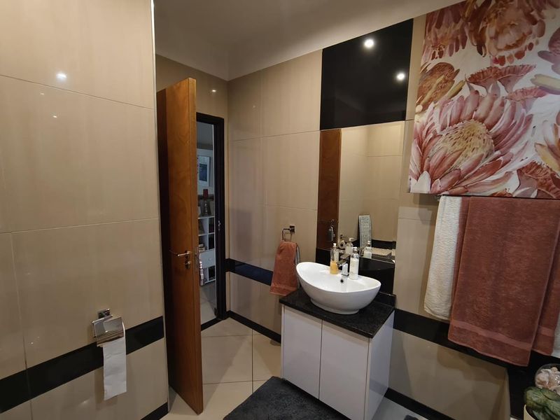 Modern bathroom featuring a vessel sink on a granite-topped vanity, complemented by neutral wall tiling and polished floor tiles.