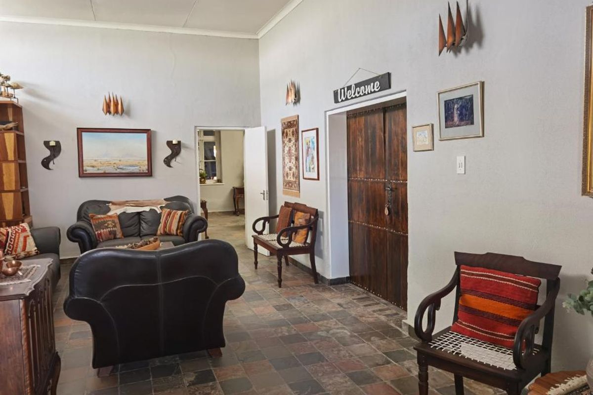 Spacious living area featuring rustic slate tile flooring and traditional double wooden doors, offering a warm and inviting atmosphere.