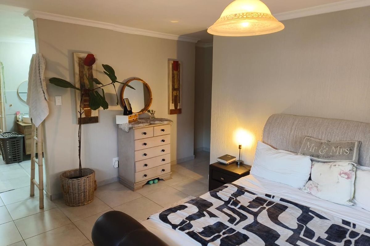 A spacious bedroom featuring tiled flooring, neutral wall finishes, and an adjoining en-suite bathroom area.