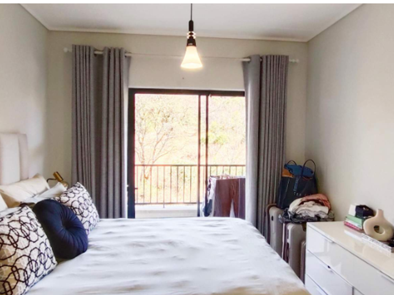 A well-maintained bedroom featuring a sliding glass door that opens to a balcony, providing natural light and outdoor access.