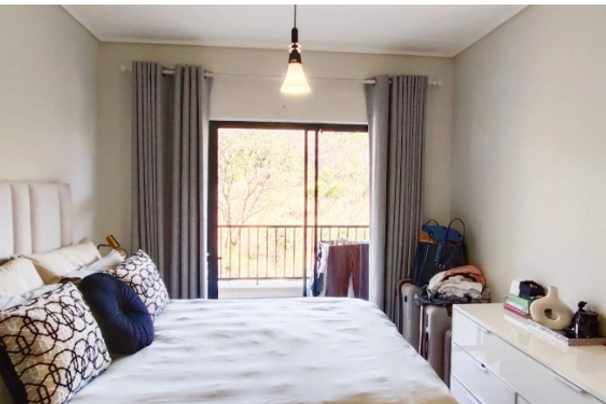 A well-maintained bedroom featuring a sliding glass door that opens to a balcony, providing natural light and outdoor access.