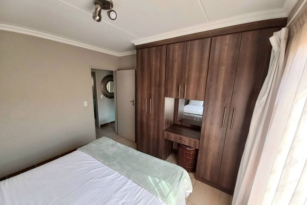 A well-maintained bedroom featuring built-in wooden cabinetry with an integrated vanity and tiled flooring.