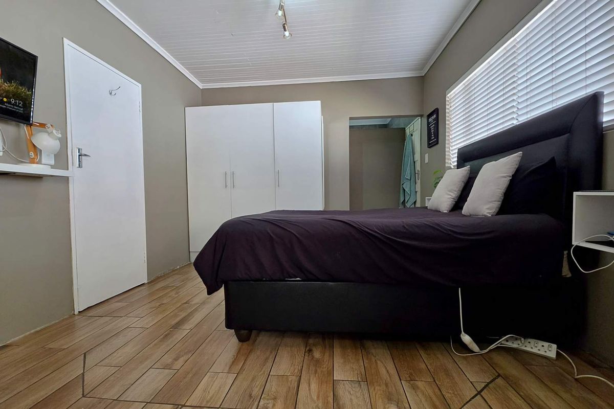 A bedroom featuring wood-look tile flooring, a built-in wardrobe, and a tongue and groove ceiling, offering a functional and neutral living space.