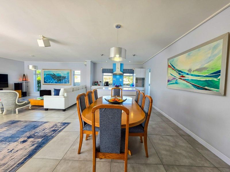Spacious open-plan living and dining area featuring tiled floors, modern kitchen cabinetry, and integrated appliances, creating a bright and functional family space.