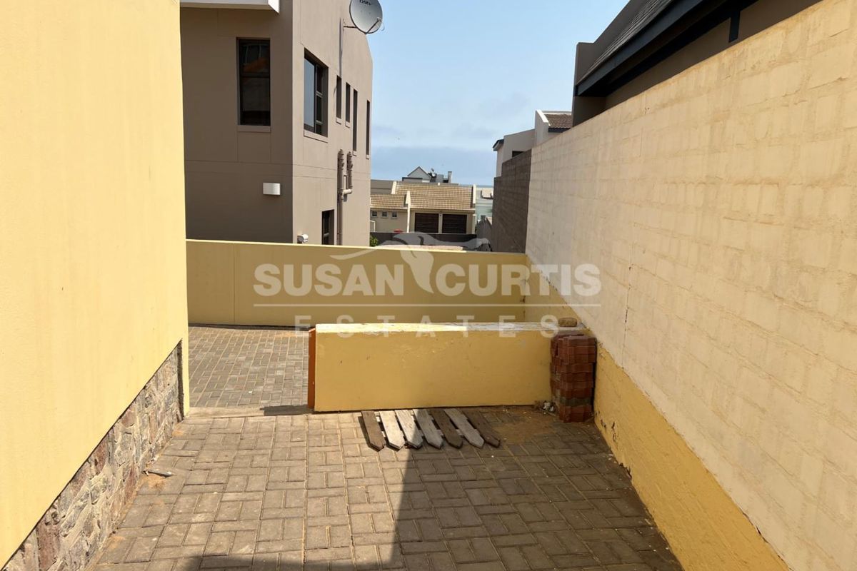 A paved rear courtyard area featuring boundary walls and a view of the surrounding residential neighborhood.