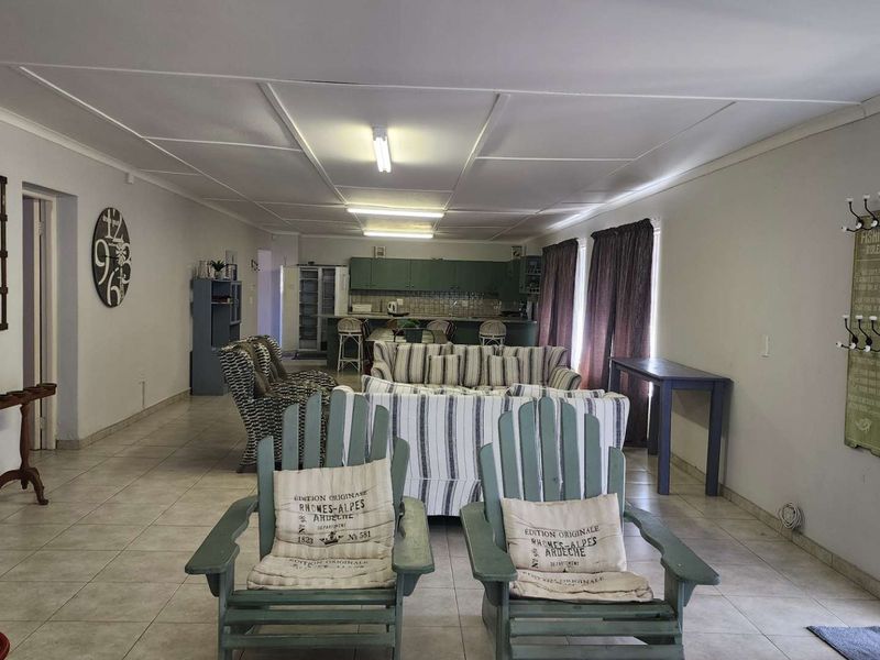 Spacious open-plan living area featuring tiled flooring and a functional kitchen with cabinetry and a central island, offering a versatile layout.