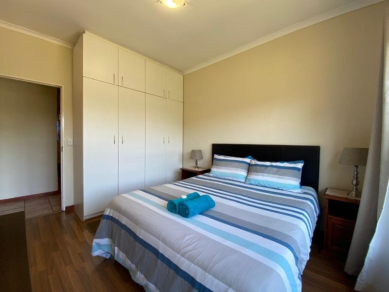 A functional bedroom featuring laminate flooring and ample built-in cupboard storage space.