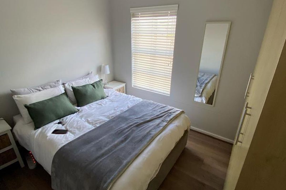 A well-maintained bedroom featuring laminate flooring, a ceiling fan, and a built-in wardrobe, offering a clean and functional living space.