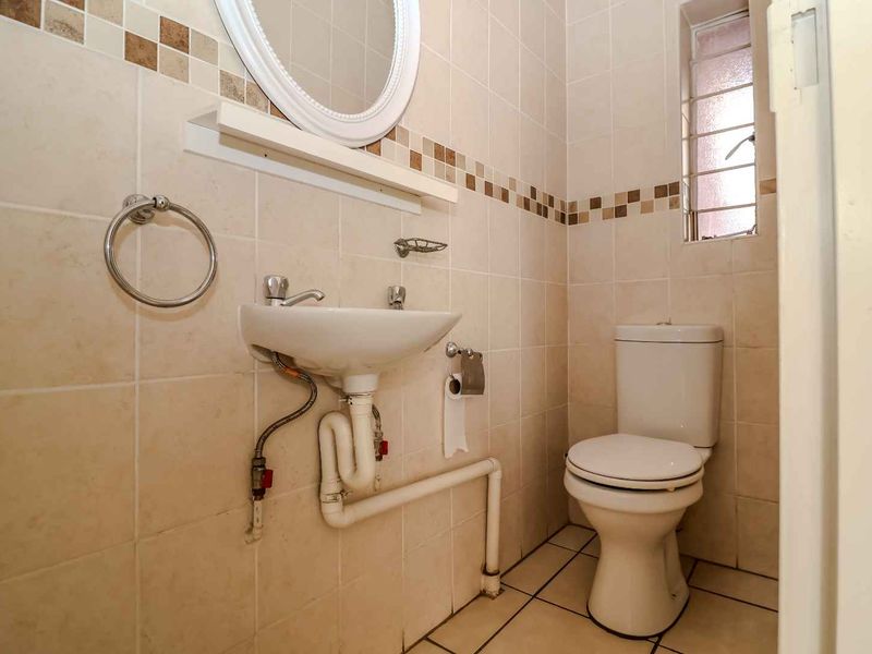 A compact guest bathroom featuring tiled walls, a wall-mounted basin, and a standard toilet, providing a functional space with neutral finishes.