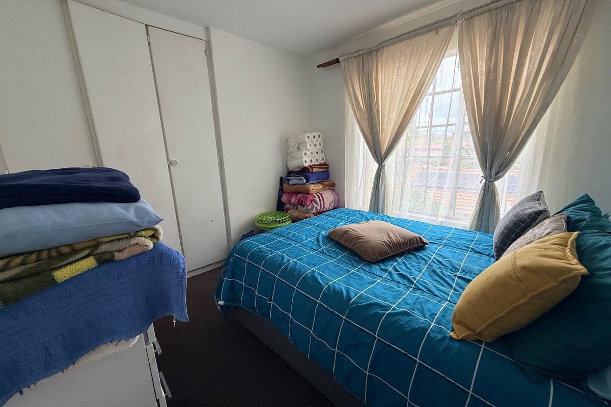 A functional bedroom featuring built-in cupboards and a window with natural light, providing a comfortable living space.