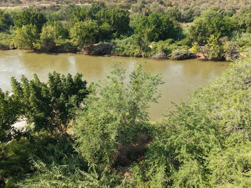 A scenic elevated view of a natural river flowing through a lush, tree-lined landscape, highlighting the property's tranquil waterfront setting.
