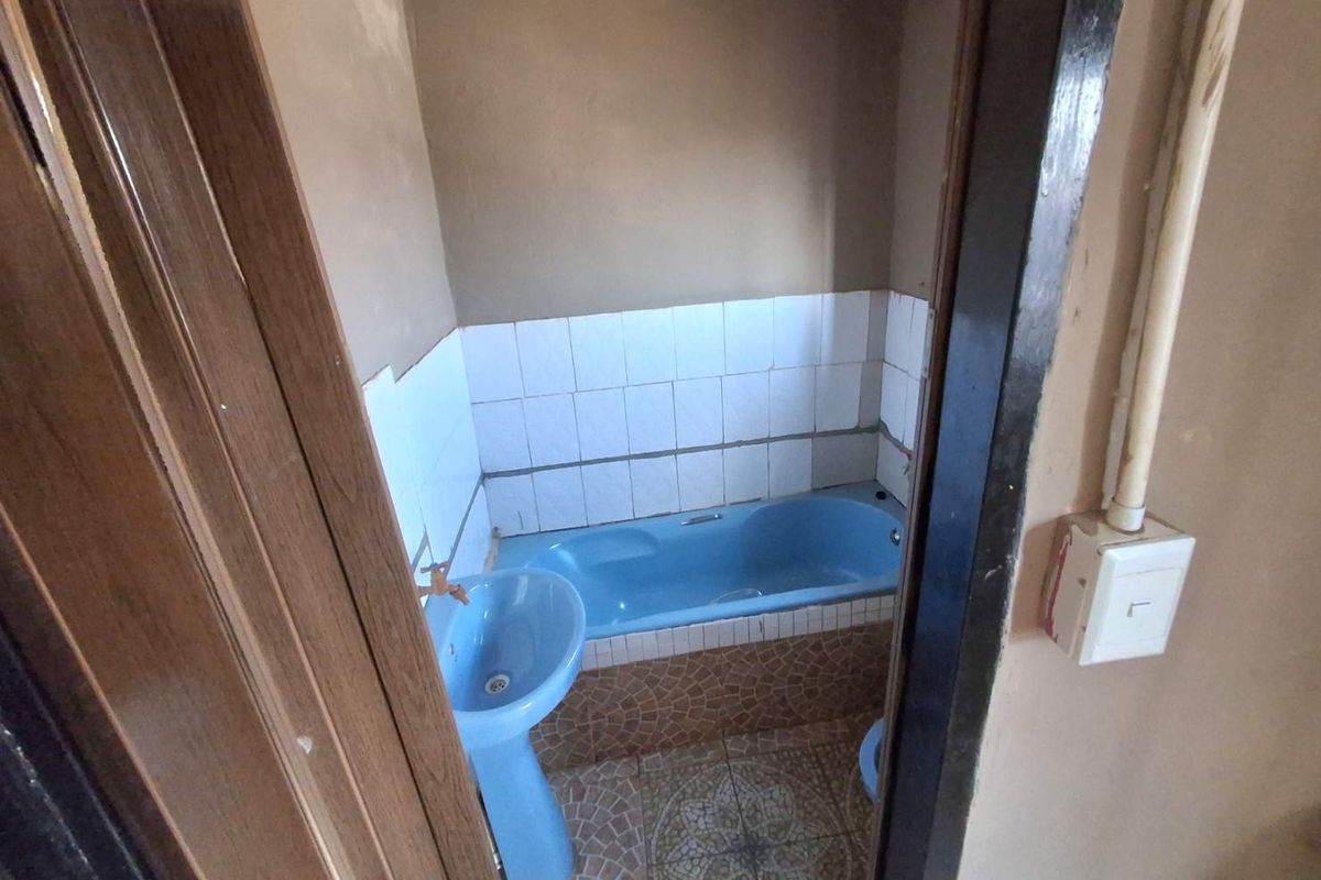 A compact bathroom featuring a blue pedestal basin and matching bathtub with tiled flooring and wall splashbacks.