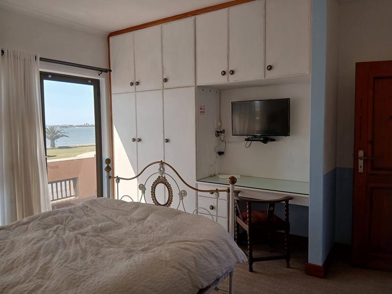 Bedroom featuring built-in cupboards, a integrated desk area, and a sliding glass door providing access to a balcony with water views.