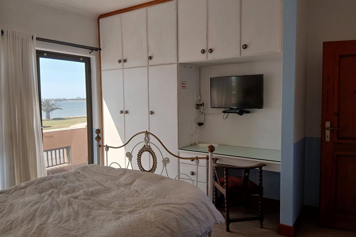 Bedroom featuring built-in cupboards, a integrated desk area, and a sliding glass door providing access to a balcony with water views.