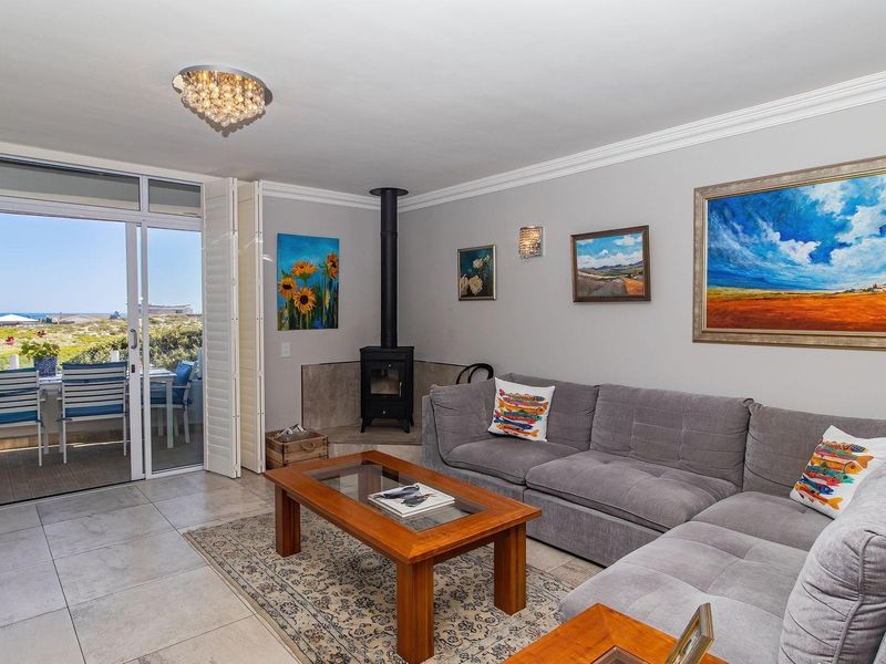 A bright living room featuring a freestanding fireplace, tiled floors, and large sliding glass doors that open onto an outdoor patio area.