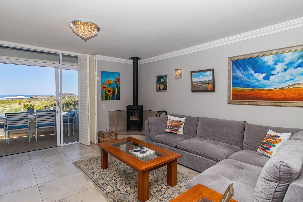 A bright living room featuring a freestanding fireplace, tiled floors, and large sliding glass doors that open onto an outdoor patio area.