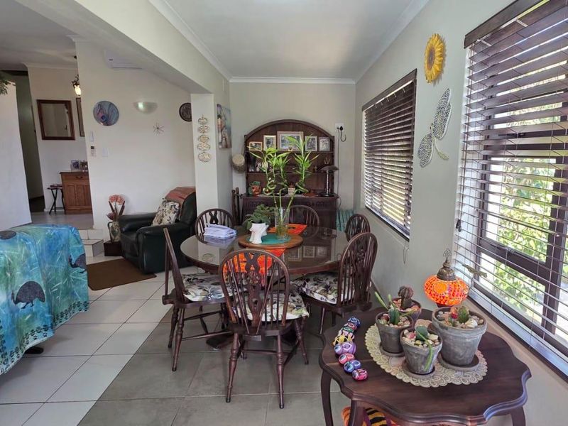 Open plan living and dining area featuring tiled flooring, large windows with venetian blinds, and an integrated air conditioning unit.