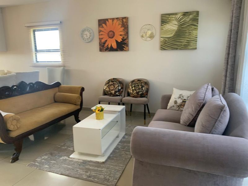 A comfortable living room area featuring tiled flooring and a window with fitted blinds, providing a neutral space for relaxation.