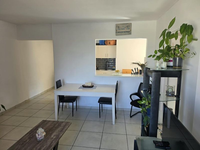 Open plan living and dining area featuring neutral tiled flooring and a convenient pass-through window connecting to the kitchen space.