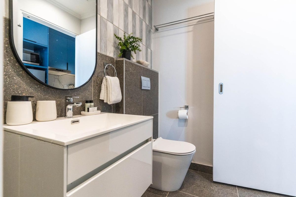 Modern bathroom featuring a wall-hung vanity, contemporary basin, wall-mounted toilet, and stylish tiled splashback with a sleek sliding door.