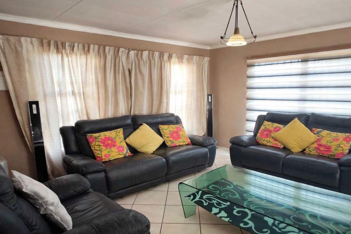 A comfortable living room featuring tiled flooring, neutral wall tones, and window blinds, providing a functional and well-lit space for relaxation.
