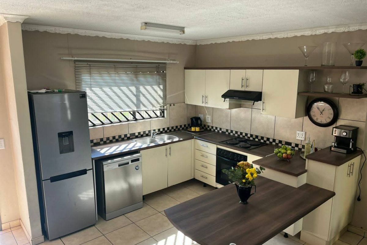 Functional kitchen featuring built-in cabinetry, integrated hob and oven, double sink, and tiled flooring with a breakfast counter.