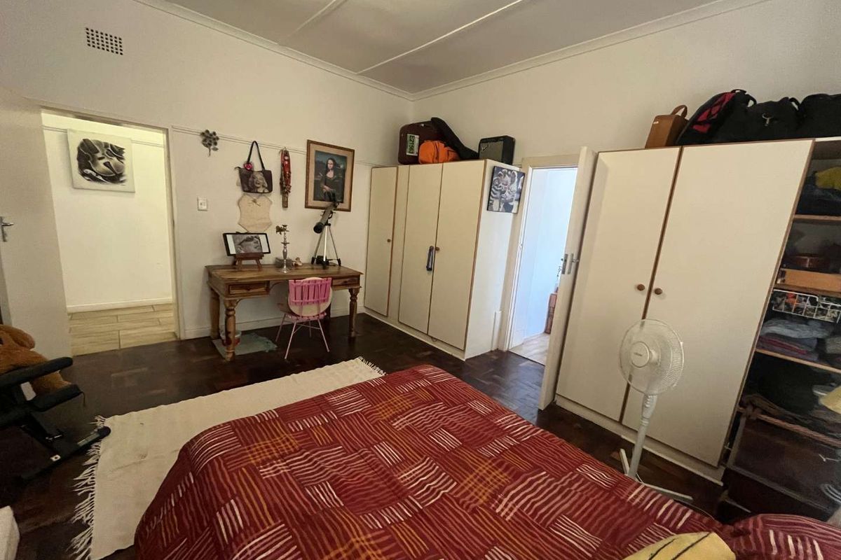 A bedroom featuring parquet flooring, built-in cupboards, and classic cornicing, offering a functional space with potential for modernization.