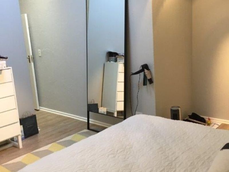 A well-lit bedroom featuring modern track lighting and laminate flooring, offering a clean and neutral living space.