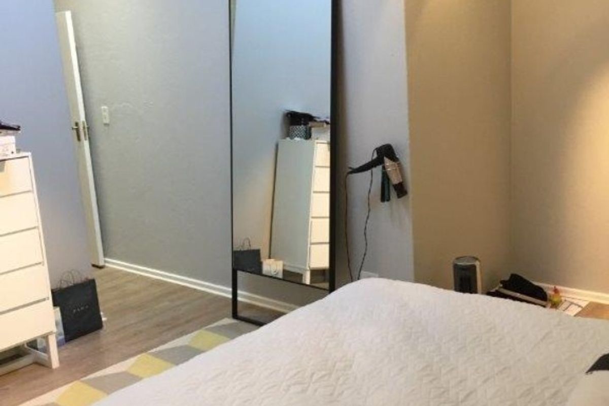 A well-lit bedroom featuring modern track lighting and laminate flooring, offering a clean and neutral living space.