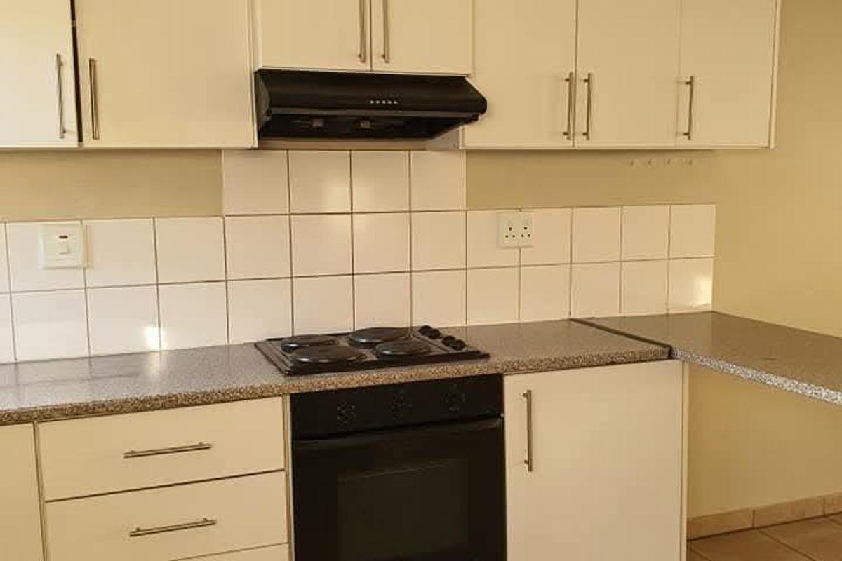 A functional kitchen featuring white cabinetry, laminate countertops, a built-in oven, electric hob, and a tiled backsplash.