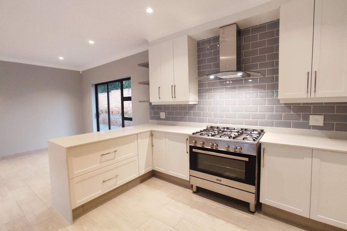 Modern kitchen featuring white cabinetry, quartz countertops, subway tile backsplash, and a stainless steel gas stove with an integrated extractor fan.