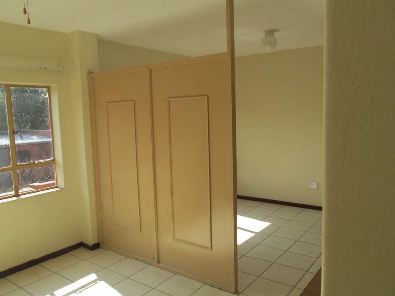 An empty bedroom featuring tiled flooring and a built-in room divider, offering a blank canvas for potential renovation or restyling.
