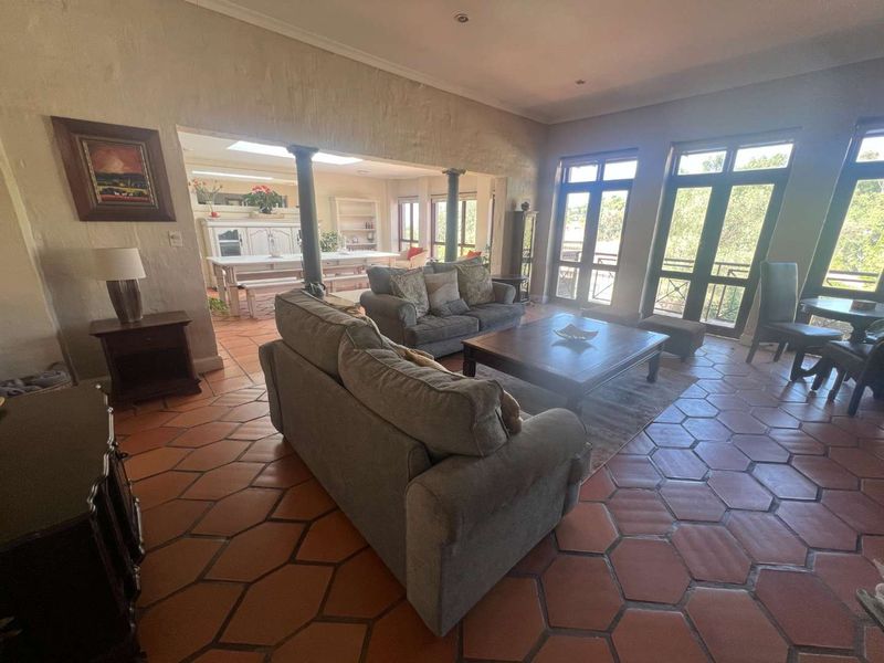 Spacious open-plan living and dining area featuring traditional terracotta floor tiles, large windows for natural light, and structural columns connecting the two spaces.