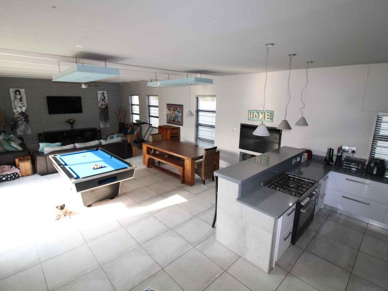 Spacious open-plan living area featuring a modern kitchen with stone countertops, gas hob, built-in oven, and tiled flooring throughout.