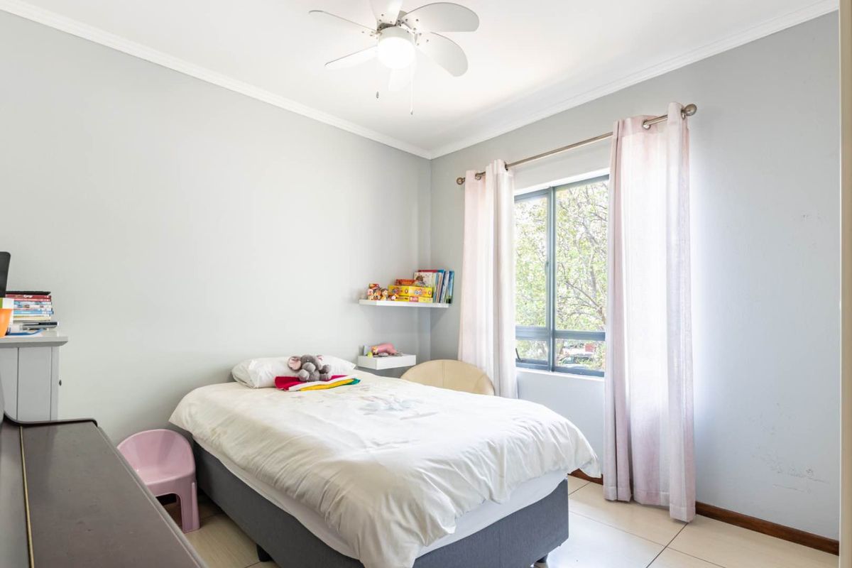 A bright bedroom featuring tiled flooring, a ceiling fan, and a window with natural light.