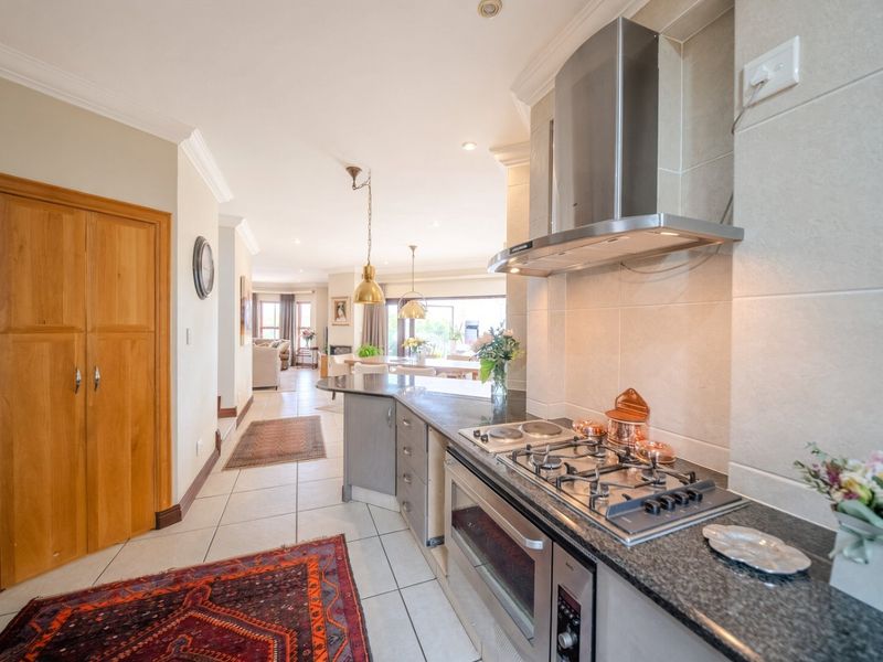 Open-plan kitchen featuring granite countertops, gas hob, built-in oven, and stainless steel extractor fan, flowing seamlessly into the adjacent living and dining areas.
