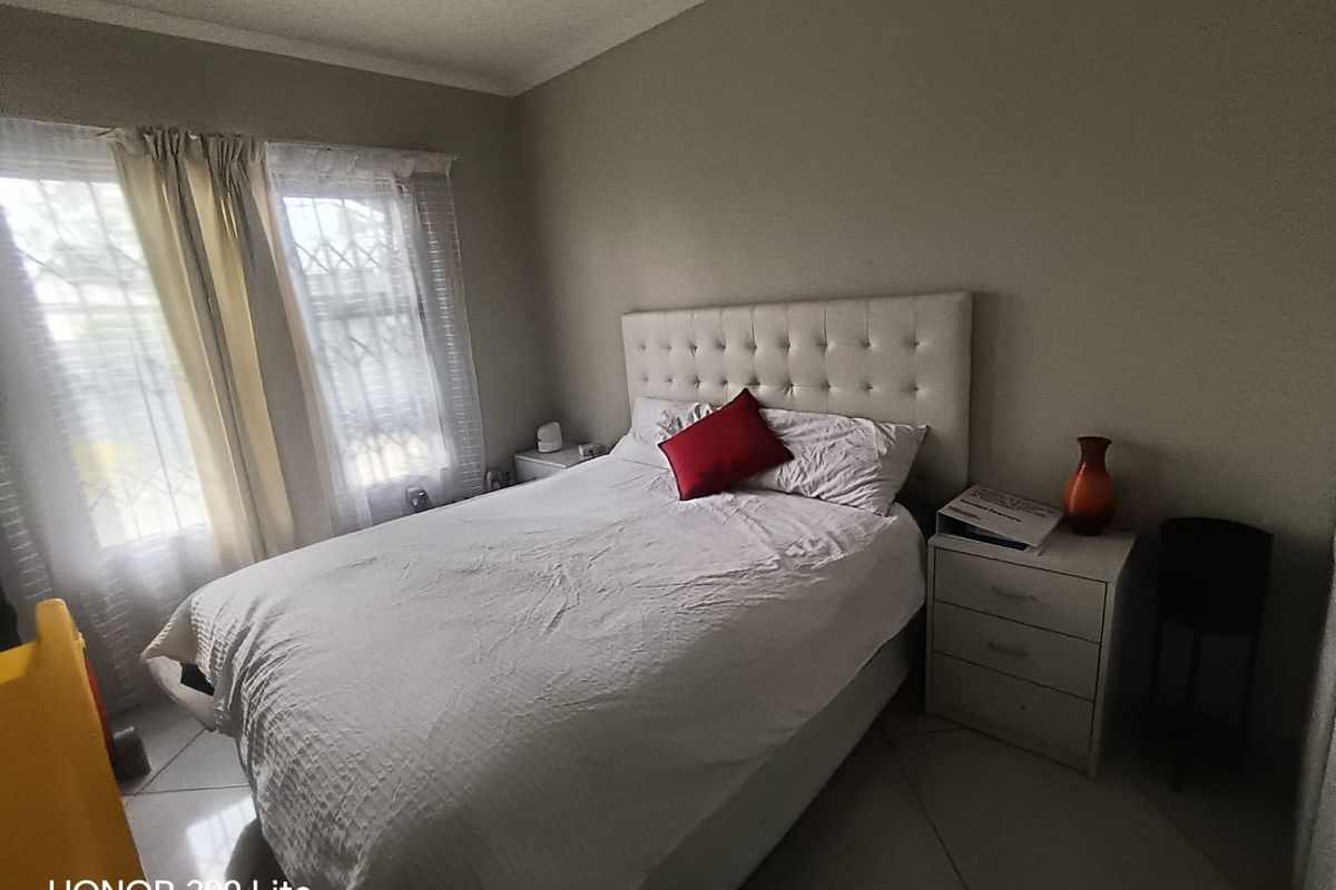 A bedroom featuring tiled flooring and security bars on the windows, providing a functional and secure living space.