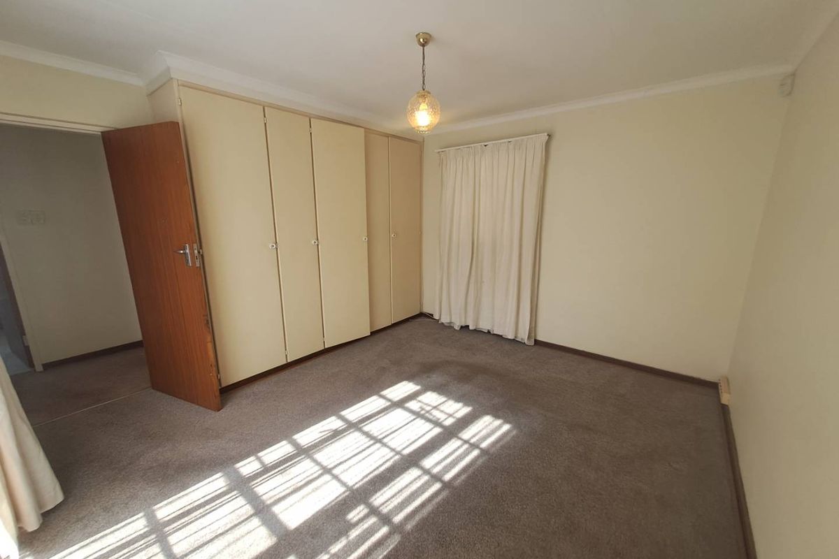 A spacious bedroom featuring built-in cupboards, neutral wall finishes, and carpeted flooring, offering a blank canvas for personalization.