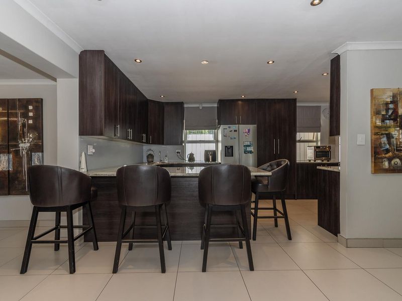 Modern kitchen featuring dark wood cabinetry, granite countertops, a functional breakfast bar, and recessed lighting, creating a sleek and cohesive culinary space.
