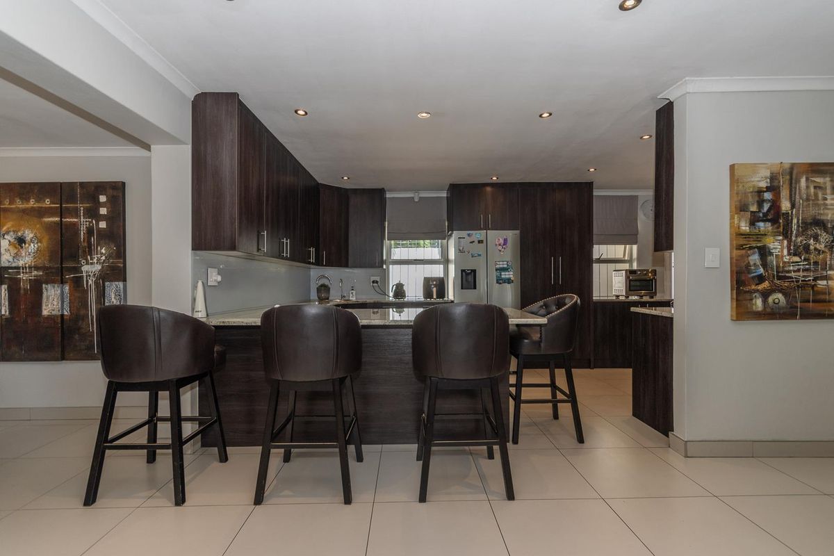 Modern kitchen featuring dark wood cabinetry, granite countertops, a functional breakfast bar, and recessed lighting, creating a sleek and cohesive culinary space.