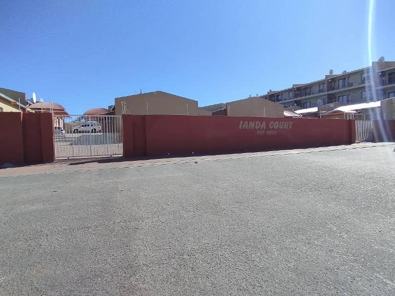 Street view of the Ianda Court townhouse complex entrance, featuring a perimeter wall, electric fencing, and gated access.